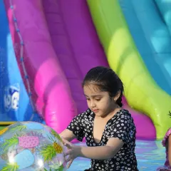 A quiet moment of play amidst the splashing. A young girl enjoys playing with an inflatable ball in the cool water of our summer pool.