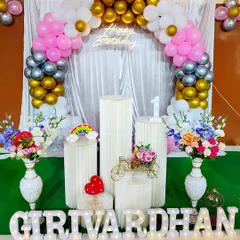 This pastel-themed ring arch uses pink, white, gold, and silver balloons. The decoration is finished with marquee letters, display pedestals for the cake, and fresh flower vases.