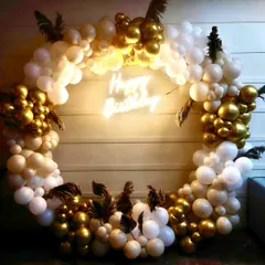 Elegance in every detail. This sophisticated birthday setup features a beautiful ring of white and gold chrome balloons, accented with delicate pampas grass and a warm 'Happy Birthday' neon sign for a touch of modern class.