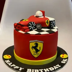 For the racing enthusiast, a custom Ferrari-themed birthday cake. This cake features a sculpted Formula 1 car on top of a red fondant base with the iconic Ferrari logo.