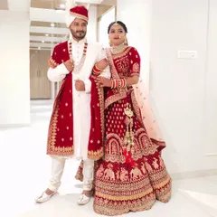 This full-length shot shows how the groom's white and red sherwani is perfectly complemented by the bride's red lehenga. A coordinated look makes for stunning wedding photos.