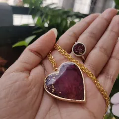 A matching jewelry set I created for a client using their own rose petals. The set includes a heart-shaped pendant and a simple round ring, both featuring deep red petals with flecks of gold leaf.