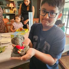 A young boy proudly displays his beautifully crafted and decorated Ganesha idol. The concentration and pride on his face say it all.