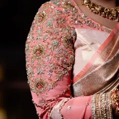 A close-up of the sleeve of a peach organza blouse. The entire sleeve is heavily embroidered with zardosi, beads, and threadwork, creating a rich and luxurious texture that feels incredible to wear.