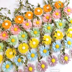 A vibrant assortment of daisy wax sachets in a rainbow of colors, part of a large baby shower gift box order.