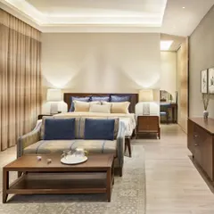A serene master bedroom at the Max128 apartment. The design combines warm wood tones, soft textiles, and subtle Indian motifs to create a peaceful and luxurious personal retreat.
