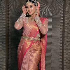 A happy bride in her traditional South Indian look. The pink Kanchivaram is draped to perfection, with neat pleats and a secure pallu that stays in place all day.