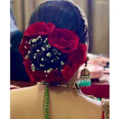 A detailed close-up of the red rose and baby's breath arrangement on a traditional bridal bun.