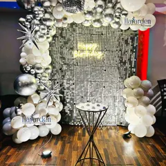 A dazzling disco-themed party with a silver sequin backdrop. The decor is accented with silver and white balloons, starburst foils, and a disco ball for that perfect retro vibe.