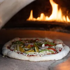 The heart of Italian cooking is simplicity and quality. Here, a fresh vegetarian pizza with a sourdough base and vibrant toppings is prepared in our authentic wood-fired oven, delivering a rustic and gourmet taste of Italy to your celebration.