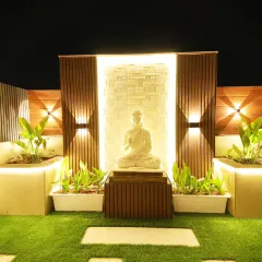 A tranquil zen corner in our Sushant Lok project, with a beautifully lit Buddha statue set against a textured wall and surrounded by illuminated planters.