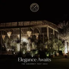 Elegance awaits. A stunning outdoor venue at night, set for The Gourmet Fest 2023, with grand chandeliers and lush greenery. We transform any space into a breathtaking setting for an unforgettable celebration.