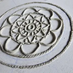 A close-up of a Lippan art piece in progress, showing the delicate clay work that forms the base of the design. We teach you how to create these traditional patterns before the mirrors are added.