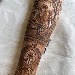 For me, mehendi is devotion. This full-sleeve design features a detailed portrait of Radha and Krishna on a swing, surrounded by divine motifs like peacocks, lotuses, and cows, creating a piece of wearable spiritual art.