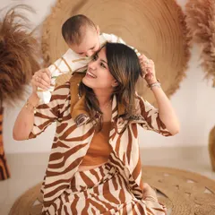 The joy in a mother's eyes as she plays with her baby. This shot from a styled studio session highlights their connection, with the mother's animal-print outfit adding a fashionable touch to the earthy decor.