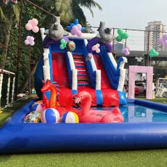 An inflatable pool complete with a slide, a pink flamingo float, and other fun pool toys.