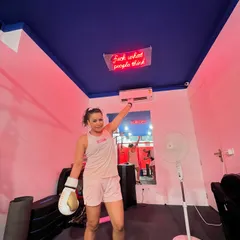 The neon sign on our ceiling says it all: "Fuck what people think." A client celebrates her workout, feeling empowered and confident in a space that encourages you to be yourself.