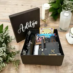 A beautifully curated gift box for him, personalized with the name "Aditya." It includes a matching black tumbler, a vegan leather wallet and keychain with custom charms, and a small photo frame.