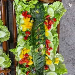 For seafood lovers, I offer special platters like this whole grilled fish, marinated in a green herb masala and garnished with fresh vegetables. It's a healthy and delicious option for any party.
