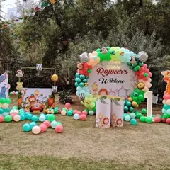 An outdoor 'Wild One' jungle-themed first birthday party in a garden setting, complete with a custom backdrop and character cutouts.