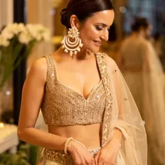 A candid moment captured, showing the intricate details of the makeup and hair. The soft glam makeup and sleek bun perfectly complement her heavily embellished blouse and statement earrings.