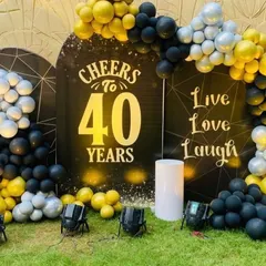 A bold and stylish 40th birthday celebration. This outdoor setup features a 'Cheers to 40 Years' backdrop, framed by a black, yellow, and silver balloon arch.