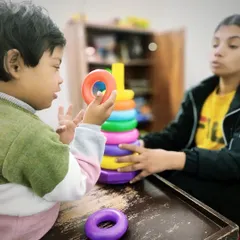 A child examines a colorful ring before placing it on the stack. This moment shows cognitive processing and motor planning, key elements we target in our occupational and speech therapy sessions.