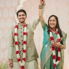 A triumphant and joyous moment as the newly engaged couple raises their hands, celebrated with traditional garlands, marking the official start of their journey.