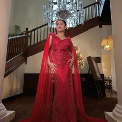 A full-length shot capturing the drama and elegance of this red gown look. The bold makeup and sophisticated styling create a powerful and unforgettable bridal statement.
