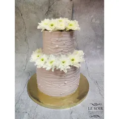 A four-kilogram Vanilla Caramel two-tier cake designed for Smriti's special day. The cake features a textured lilac buttercream and is crowned with beautiful fresh white chrysanthemums for a simple yet stunning effect.