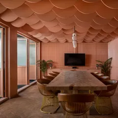 This private lounge is wrapped in a continuous wash of peach tones, from the fluted walls to the scalloped ceiling. The design creates a soft, feminine, and cinematic calm, a quiet escape that uses monolithic color and gentle curves to shape an intimate and memorable experience.