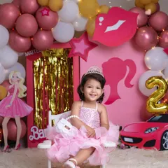 A princess in her pink palace. This little girl, dressed in a beautiful ruffled dress and a tiara, is the star of her Barbie-themed birthday celebration.