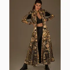 A high fashion studio portrait showcasing an intricate, floor-length coat by Nighat Izhar Designs. The powerful stance and dramatic lighting are central to this editorial look, blending traditional gold embroidery with a modern silhouette.