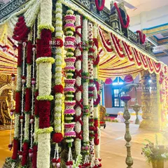 A close-up view of a magnificent traditional South Indian wedding mantap. The detailed pillars, adorned with layers of fresh flowers in red, white, and yellow, showcase the incredible artistry and craftsmanship of our team.