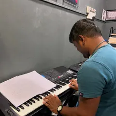 An adult student practices from sheet music during his keyboard lesson. We emphasize learning to read music to build versatile and independent musicians.