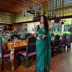 A solo shot of my Teej brunch look. The emerald green leheriya saree is paired with a simple black sleeveless blouse, which makes the traditional print feel modern and chic. The look is completed with a matching green clutch.