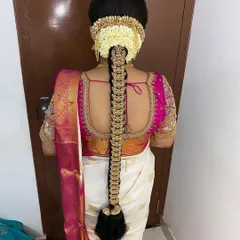 For this Muhurtham look, I created a classic braid adorned with traditional temple jewellery and a neat arrangement of jasmine flowers. This style is a perfect match for the bride's elegant white and pink silk saree.