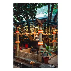 Delicate floral hangings made from palm leaves and marigolds adorn a traditional courtyard space for a naming ceremony. The decor is light, natural, and celebratory.