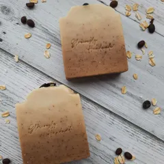 A top-down view of my Scrubby Coffee soap, made with real coffee grounds for exfoliation and creamy oat milk for moisture. I arrange whole coffee beans and oats around the bars to show you the simple, wholesome ingredients inside.