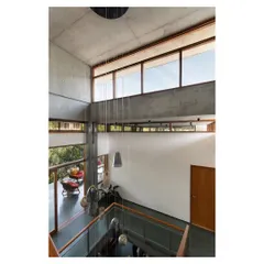 A view from the upper level looking down into the triple-height volume. The large windows and clerestories are strategically placed to flood the home with natural light throughout the day.