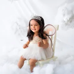 A little angel sitting on her throne in the clouds. This little girl's happy smile and the whimsical setup create a truly magical and adorable portrait.