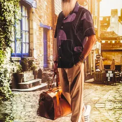 A timeless and charming portrait. The projected European street scene and warm, golden light create a sophisticated and relaxed atmosphere for this classic men's fashion look.