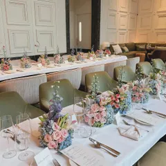 A long shot of the dining setup for the Jimmy Choo press gathering. The clean white linens and minimalist place settings allow the pastel floral arrangements to stand out, creating a chic and polished look.