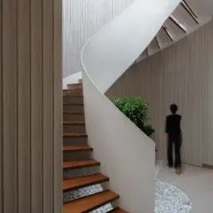 I believe staircases can be sculptural centerpieces. This helical staircase in a contemporary penthouse creates a striking visual impact with its dynamic, swirling form contrasted against the clean, linear aesthetic of the fluted wood wall.