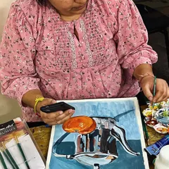 A student works on a still life painting of a metallic coffee pot, using her phone for reference. Our studio is a space for focused, individual learning.