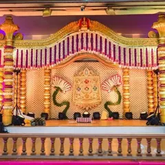 A wedding mantapa featuring unique lotus-shaped floral motifs and a backdrop of delicate flower strings. The design combines traditional elements with artistic floral work for a distinctive look.