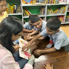 A close-up of children pointing at illustrations during a story session. Interactive reading helps them connect deeply with the narrative, making the experience more personal and impactful.