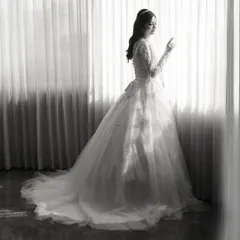 A classic black and white portrait of the bride in her beautiful white gown, looking out the window.