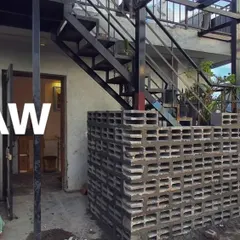 A raw, "before" shot of a terrace space, with exposed brick and a basic metal staircase, ready for a complete makeover.