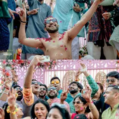 The wild energy of a Haldi celebration! Friends and family dancing, celebrating, and showering the groom with petals in a moment of pure, uninhibited fun.